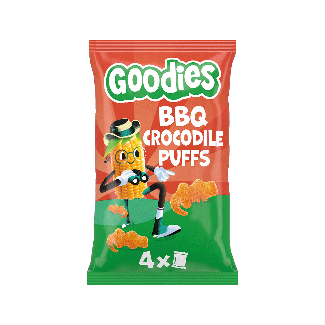 A red and green packet of Goodies BBQ Crocodile Puffs featuring a cartoon corn character wearing a hat and glasses, standing next to puffed snacks shaped like crocodiles. The text reads “Goodies BBQ Crocodile Puffs” and “4 x 1”.